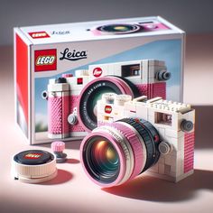 a pink lego camera sitting in front of a box with the lid open and lens attached to it