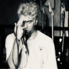 black and white photograph of a man holding his head in front of his face while talking on the phone