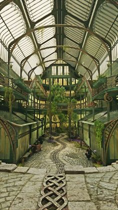 the inside of a building with lots of windows and plants growing on the sides of it