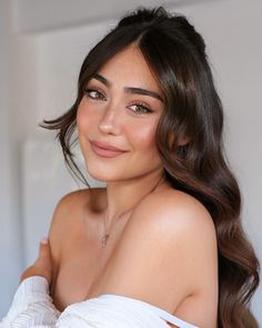 a beautiful young woman with long brown hair wearing a white dress and smiling at the camera