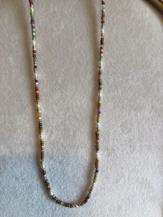 a long beaded necklace is displayed on a mannequin