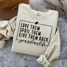 two sweatshirts and a hat sitting on the ground next to each other, one has a message that says love them spoil them give them back grandmalife