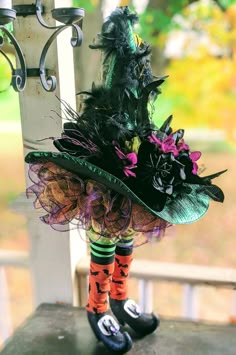 a doll is dressed in black and green with colorful feathers on her hat, leggings and socks