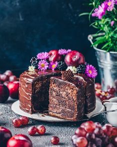 a piece of chocolate cake on a plate with flowers and cherries in the background