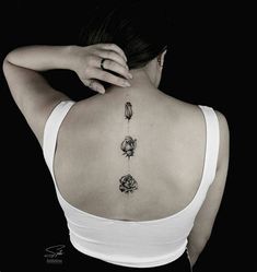 the back of a woman's neck with three flowers on her left side and four petals on her right shoulder