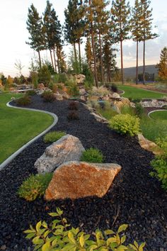 a large rock sitting in the middle of a lush green field next to some trees