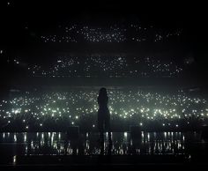 the silhouette of a person standing in front of a stage with bright lights on it