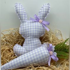 a stuffed rabbit sitting in hay next to a plant