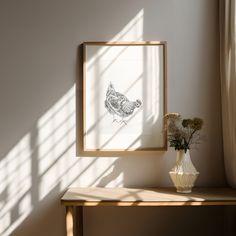 a vase with flowers sitting on a table next to a framed photograph