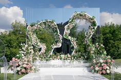 an outdoor wedding ceremony setup with flowers and greenery on the ground, in front of a large mirror