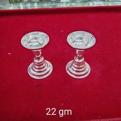 two glass candlesticks sitting on top of a red velvet covered box with measurements