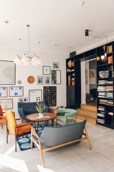 a living room filled with lots of furniture and pictures on the wall next to bookshelves