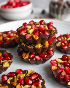 chocolate cups filled with nuts and pomegranates on top of a white plate