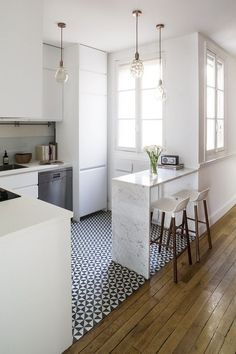 a white kitchen with black and white checkered flooring on the wooden floors is pictured in this image