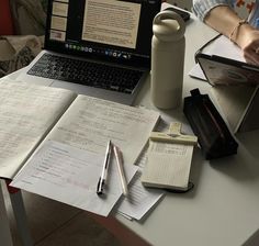 an open laptop computer sitting on top of a desk next to notebooks and papers