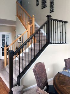 a dining room table and chairs under a stair case in a house with white walls