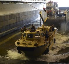 a small boat traveling down a river next to a loading dock with people on it