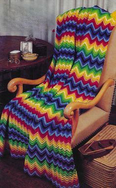 a multicolored blanket sitting on top of a wooden chair next to a table