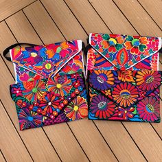 two brightly colored bags sitting on top of a wooden floor next to each other,