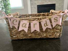 a wicker basket filled with pink and gold party decorations for a baby's first birthday