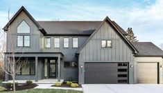 a large gray house with two garages on the front and one car parked in front