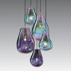 four different colored glass light bulbs hanging from a ceiling fixture with one bulb turned upside down