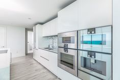 a modern kitchen with white cabinets and stainless steel appliances in the middle of the room