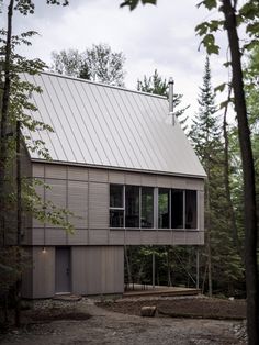 a house in the woods with lots of windows on it's roof and side walls