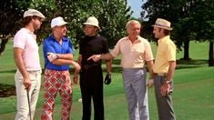 four men are talking on the golf course