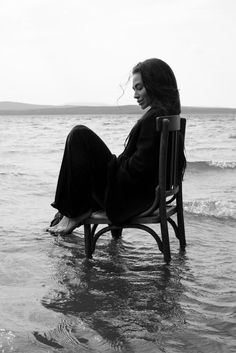 a woman is sitting on a chair in the water