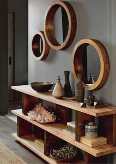 a shelf with some vases and mirrors on top of it in front of a wall