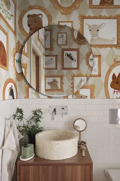 a bathroom sink with a round mirror above it and pictures on the wall behind it