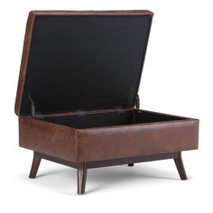 a brown leather ottoman sitting on top of a wooden table next to a white wall