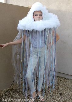 a man dressed as a cloud with streamers on his head and hands, standing in front of a wall