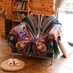 a chair with a blanket on top of it next to a pair of slippers