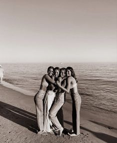 four women standing on the beach with their arms around each other