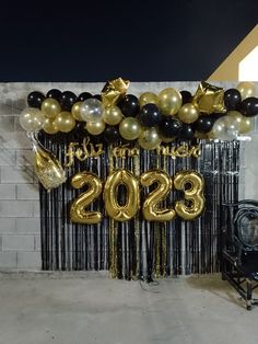 balloons and streamers decorate the entrance to a new year's eve party in gold, black and silver