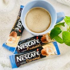 three bars of nestle coffee next to a cup of coffee on a white blanket