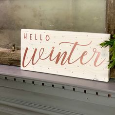 a wooden sign sitting on top of a window sill next to a potted plant