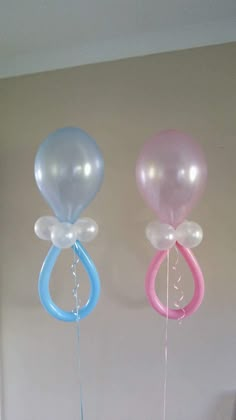 three balloons are hanging from the ceiling in different colors and shapes, one is pink, one is blue