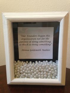 a white frame with pearls in it on top of a wooden table next to a sign