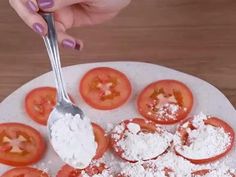 a person is spooning some powdered sugar on top of tomato slices and tomatoes