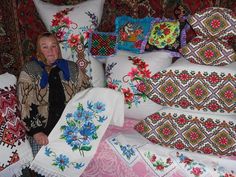 a woman is sitting on a couch covered in pillows and blankets, all decorated with flowers