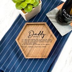 a personalized wooden coaster sits on a table with succulents and a bottle of wine