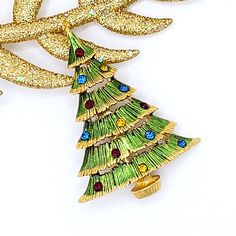 "This is a dazzling textured Christmas tree brooch pin with green enamel and gold tone, encrusted with multi-color rhinestones. Quite a classic version of holiday decoration. Beautiful Holiday jewelry. Good quality Christmas jewelry.  Multicolor crystals Christmas tree. Don't miss out on this gorgeous Brooch! 🔹 Condition: Previously owned, in excellent condition with no missing stones or gold-tone loss. The stem pin mechanism is in perfect working order. All photos are taken in macro mode. Please look carefully at all the photos as they are part of the description to be in agreement with our offer. 🔹Approximate measurements:  2-1/4\" H x 1- 5/8\" W in the widest part. 🔹 Hallmarked J.J. with a copyright symbol. 🔹 Approximate Date: - 1980s 🔹 Occasion- Christmas Holiday, Christmas Gift. Gold Christmas Gift Pins, Gold Christmas Pins For Gifts, Gold Holiday Brooch Jewelry, Gold Christmas Brooches For Festive Occasion, Copyright Symbol, Crystal Christmas Tree, Jewelry Christmas Tree, Holiday Pins, Orange Crystals