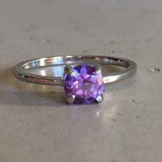 "A TINY round-shape faceted genuine Purple Amethyst hand set in a 4-prong setting featuring a tapered sterling silver shank. This beauty makes a great birthstone ring for those February Birthday gals or a lovely stackable ring for her! Wrapped in a box ready for gift-giving. (r-egt-146) Ring info ------------------------- Genuine Purple Amethyst measures 5mm Sterling Silver *Follow us @belesasjewelry on Instagram for promotions/giveaways *LIKE* us on Facebook http://www.facebook.com/Belesas to f Classic Amethyst Round Cut Birthstone Ring, Classic Amethyst Birthstone Ring With Round Cut, Modern Crystal Ring With Prong Setting, Fine Jewelry Amethyst Birthstone Ring, Round Cut, Fine Jewelry Amethyst Birthstone Ring Round Cut, Amethyst Solitaire Crystal Ring In Fine Jewelry Style, Purple Topaz Promise Ring, Modern Ruby Birthstone Ring, Formal Amethyst Birthstone Ring With Round Stone