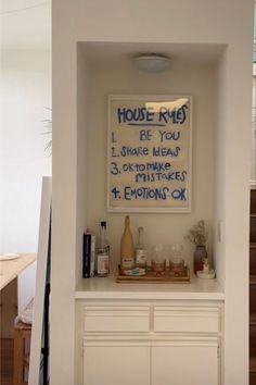 there is a sign that says house rules on the wall in front of a white cabinet