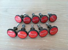 six coca - cola bottle caps are sitting on top of a wooden table with screws