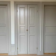 three white doors in a room with wood flooring