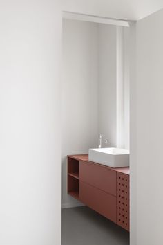 a bathroom with a sink, mirror and shelving unit in the corner between two walls